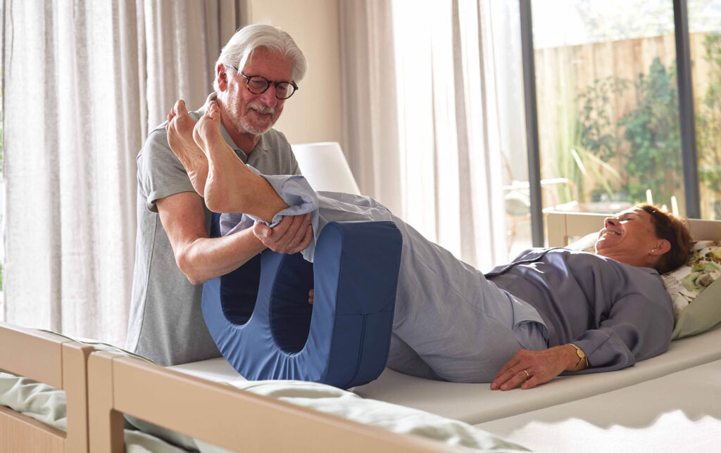 Pfleger positioniert die Beine einer Patientin für die Umlager- und Wendehilfe