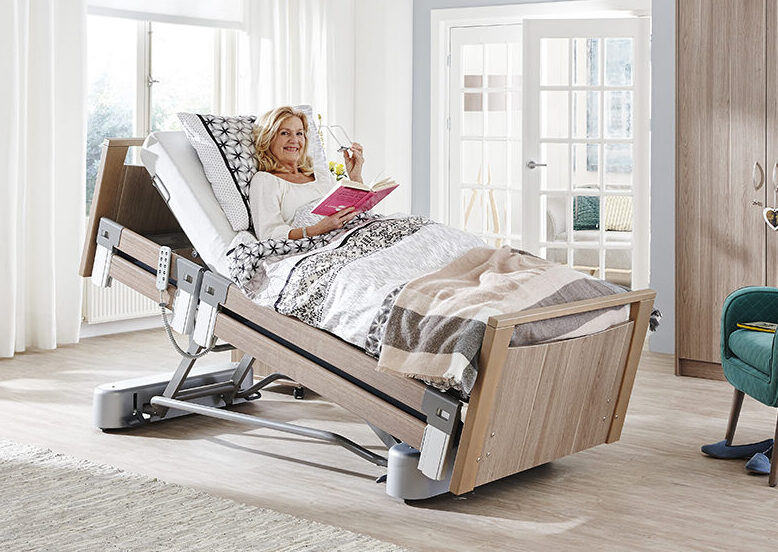 Frau liegt im Pflegebett in der Anti-Trendelenburg Position und liest ein Buch