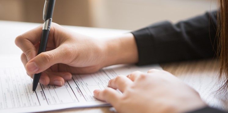 Nahaufnahme von Händen, die ein Formular ausfüllen