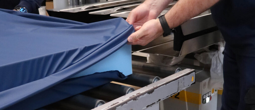 Mitarbeiter verschließt den Bezug einer Matratze