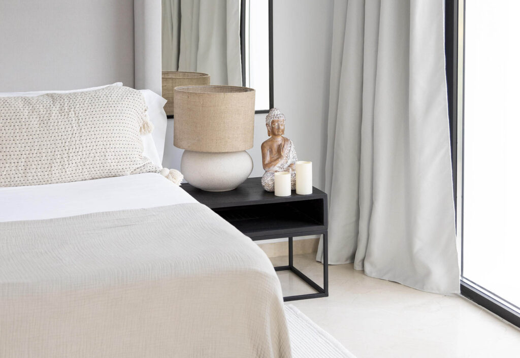 Stylisches Schlafzimmer mit einer Buddafigur und Kerzen auf dem Nachttisch