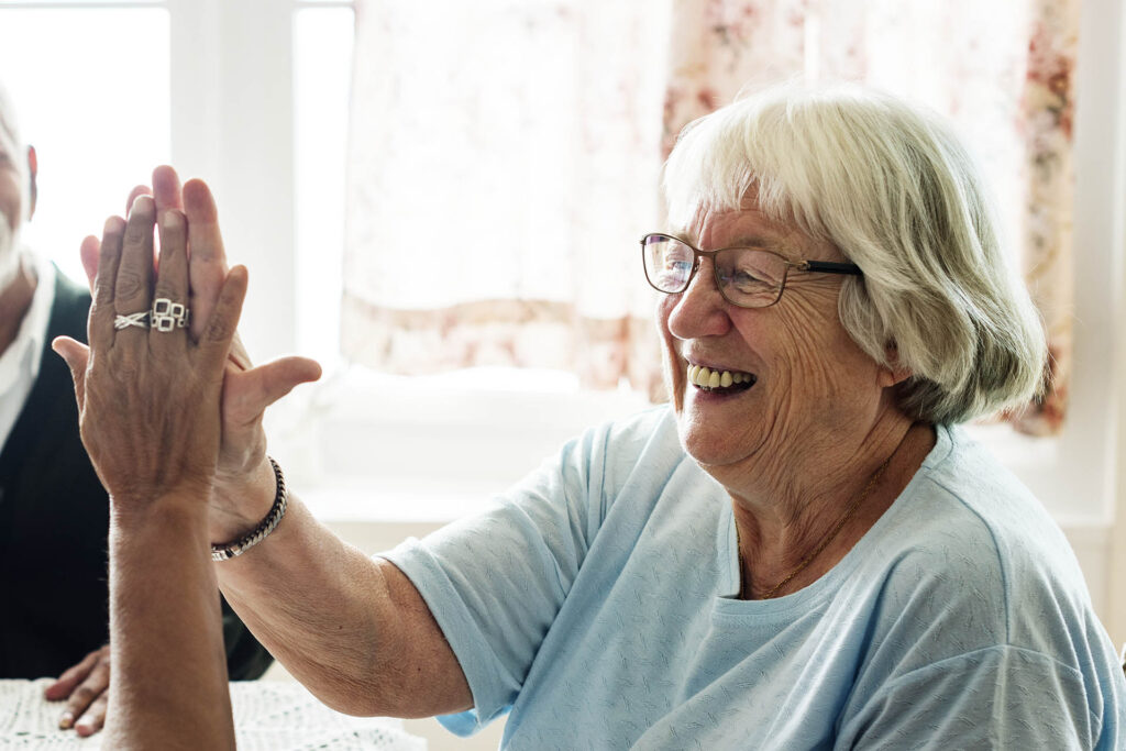 Rentnerin lacht und gibt einer anderen Person ein high five